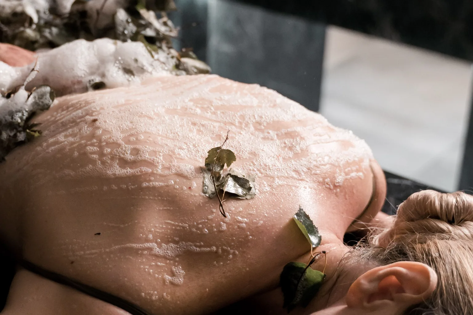 Soin exfoliant du dos avec mousse dans une ambiance spa