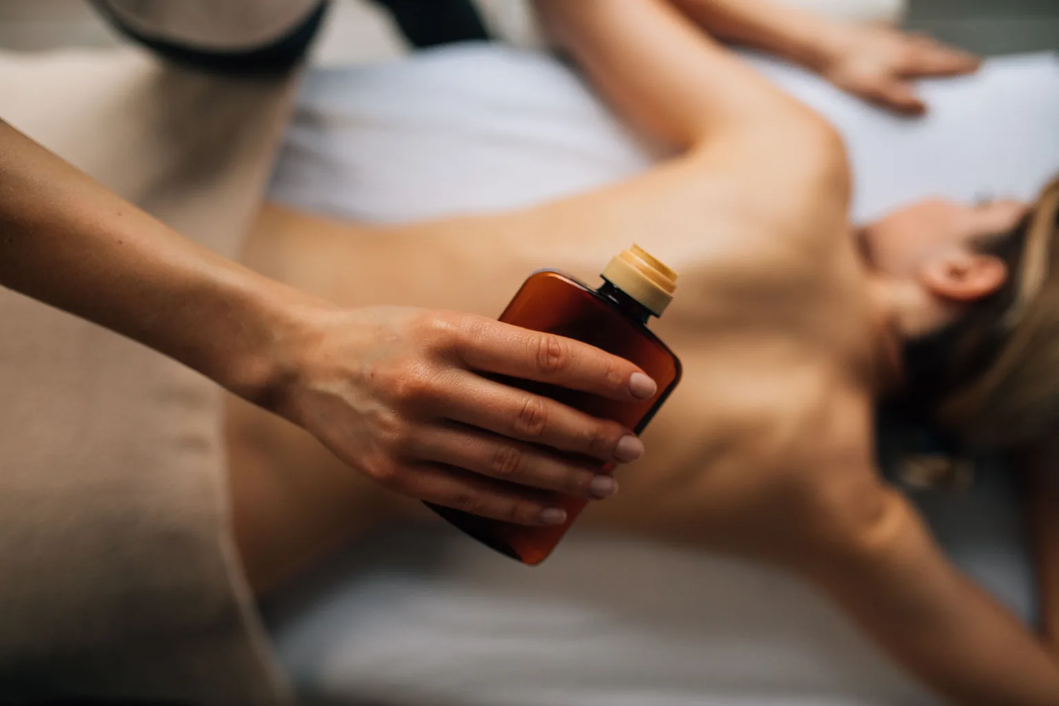 Huile de massage versée pendant un soin du corps